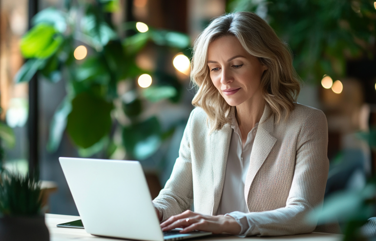 Professional woman working efficiently on laptop with focused, calm expression in modern office