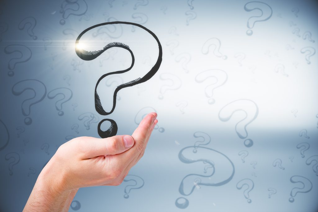 Question marks on a light blue background with a hand (palm facing upwards) holding the largest question mark.
