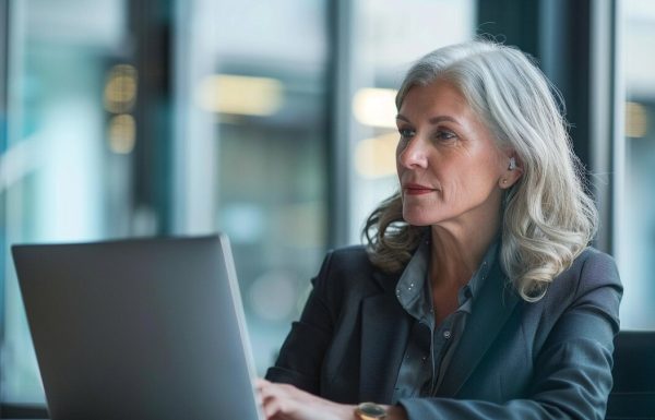 Senior executive woman reviewing presentation slides on laptop with focused analytical expression in modern office